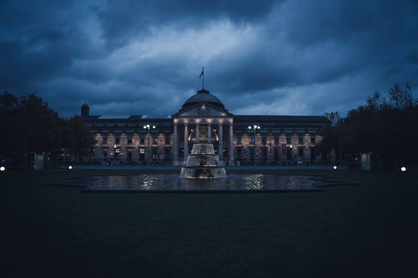 The Kurhaus in Wiesbaden at dusk, with the fountain on the Bowling Green in front